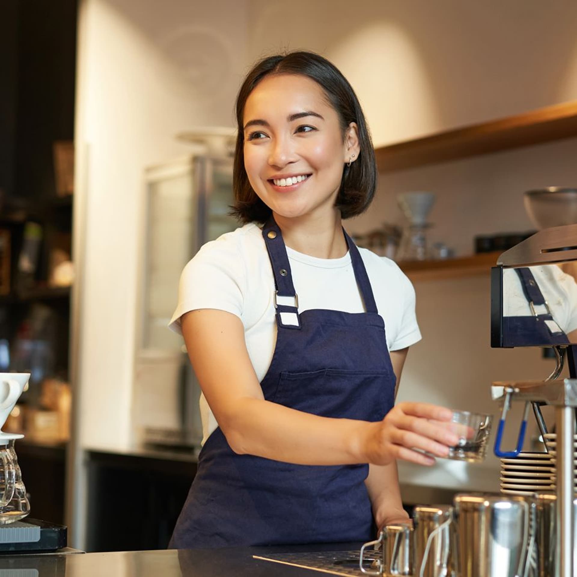 smiling-girl-barista-cafe-preparing-cappuccino-coffee-machine-steaming-milk-wearing-uniform 1.jpg